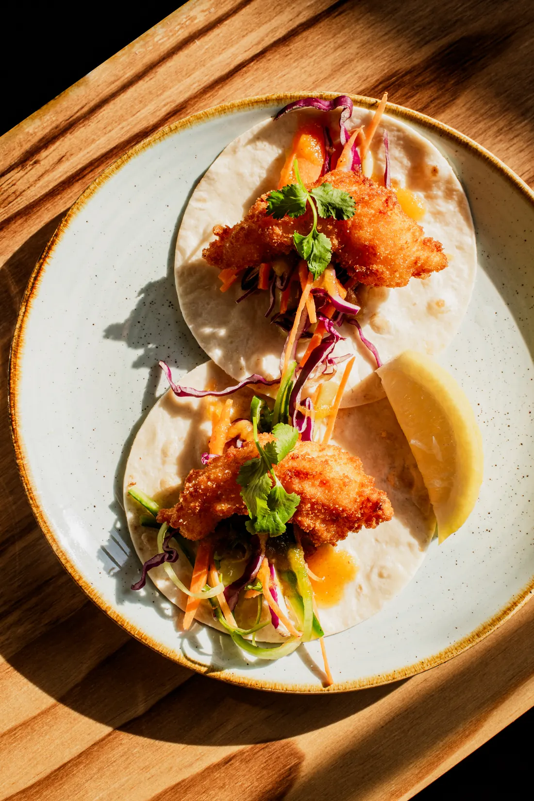 Two crispy fish tacos with slaw, coriander and lemon